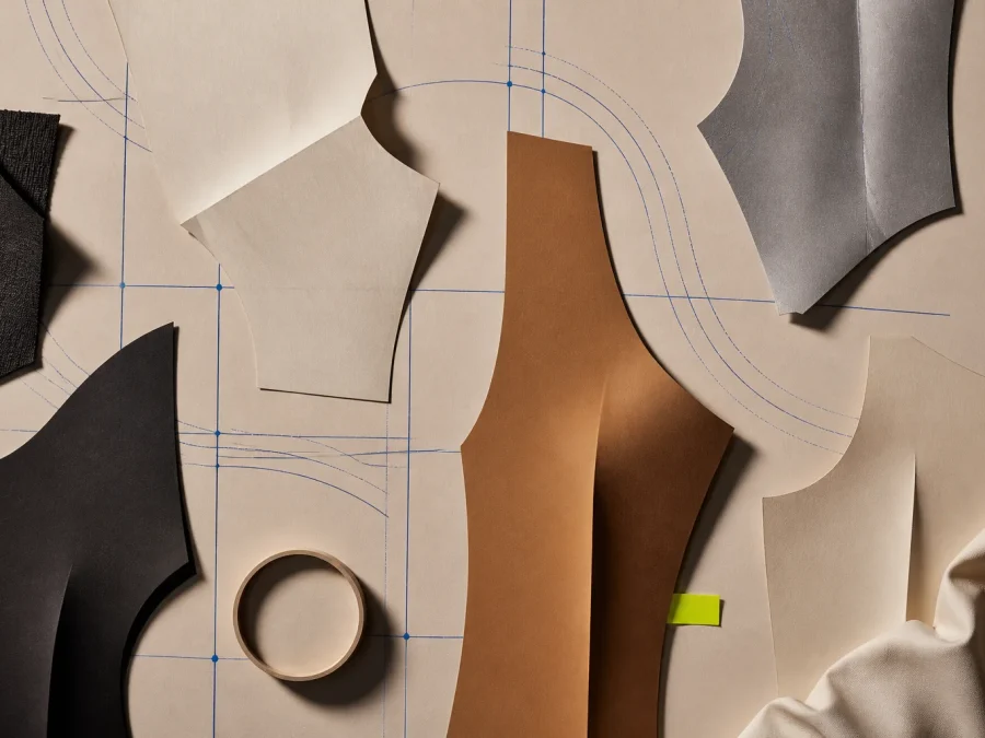 Abstract paper garment panels arranged over a warm patternmaking table with cobalt construction paths and one acid-lime human-review marker.