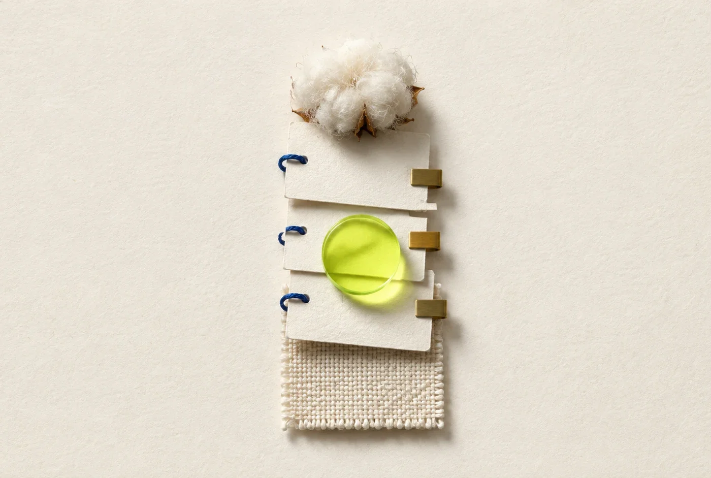 A compact stack of blank evidence cards links raw cotton to a woven swatch under a lime inspection lens.